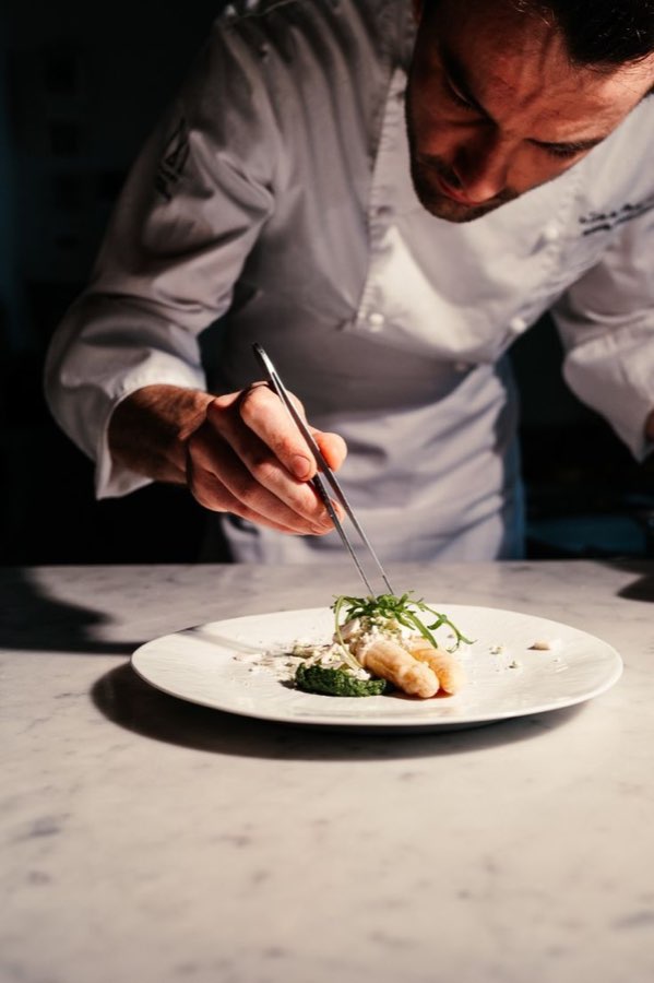 A chef finishing a plate with tweezers