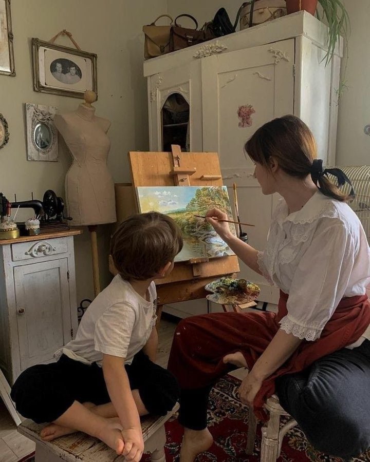 A child and a painter at an easel in a studio