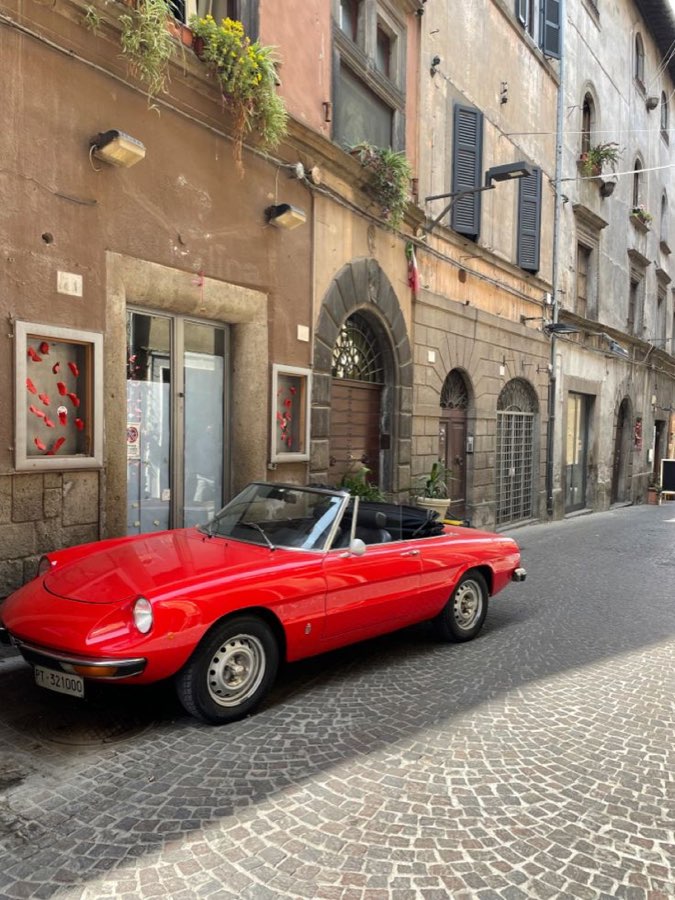 A red classic convertible on a cobbled street in Rome