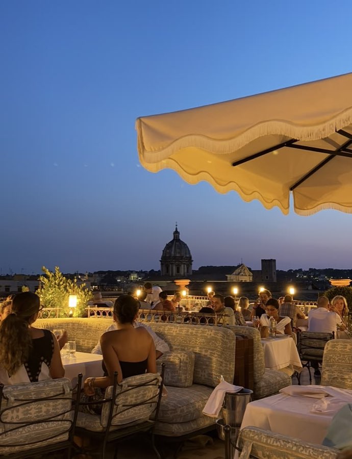 A rooftop terrace at dusk, a dome on the skyline